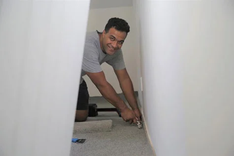 Ben Halaufia on the floor laying carpet in an Auckland residential home and installing underlay.